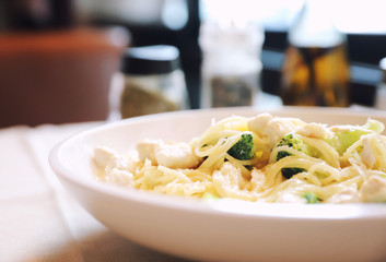 alfredo spaghetti broccoli chicken white sauce in restaurant background