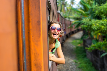 Young woman enjoying traveling by train through Sri Lanka 