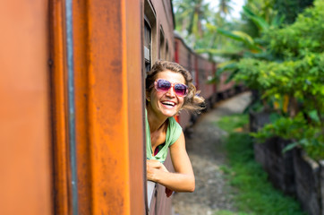 Young woman enjoying traveling by train through Sri Lanka 