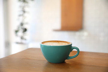 Hot cappuccino coffee in coffee shop on wooden table