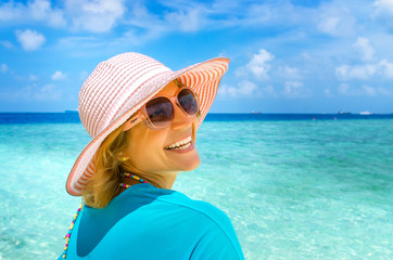 woman in fashion beachwear and hat on tropical beach on summer vacation travel.