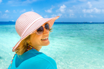 woman in fashion beachwear and hat on tropical beach on summer vacation travel.