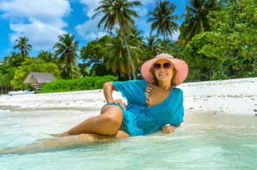 woman in fashion beachwear and hat on tropical beach on summer vacation travel.