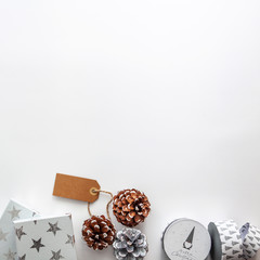 White gifts and pine cones on the white copy space background. Empty space for text, flat lay, above view. Bright simple Christmas card