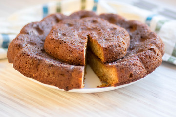 Chocolate almond pumpkin cake on white plate on colorful kitchen towel, tasty sweet dark brown biscuit