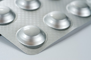 Plate with round medical pills silver color close-up shot