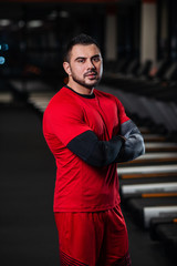 Handsome man with big muscles, posing at the camera in the gym