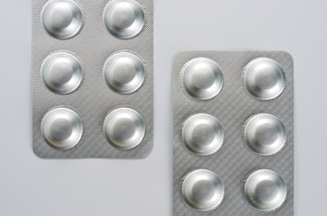 Plate with round medical pills silver color close-up shot