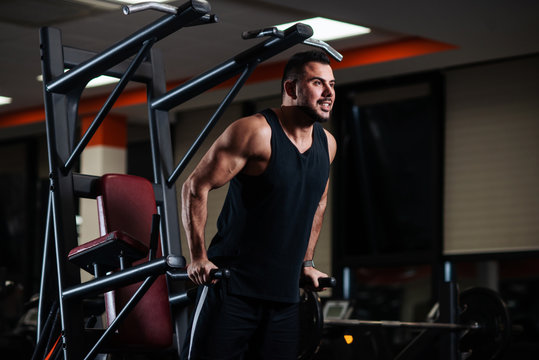 Muscular man during a workout at the gym trains the triceps on the parallel bars