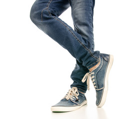 Man legs feet jeans sneakers on a white background. Isolation