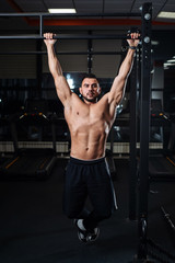 Fototapeta na wymiar Athletic man making pull-up exercises on a crossbar in the gym