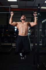 Fototapeta na wymiar Athletic man making pull-up exercises on a crossbar in the gym
