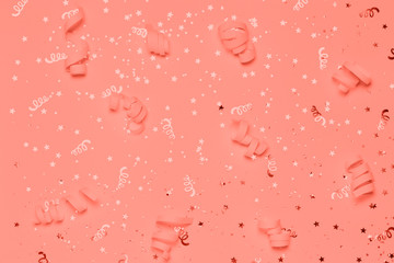 Living coral Christmas confetti and sparkles background.