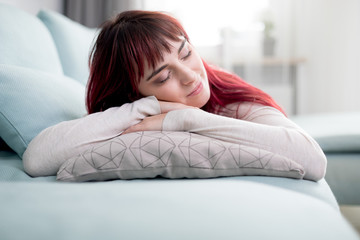 Peaceful woman resting and sleeping on sofa at home during day