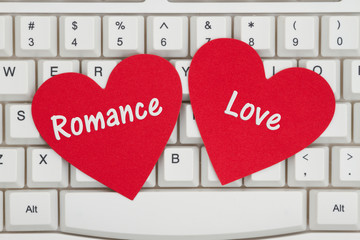 Two red hearts with text Romance and Love on a keyboard