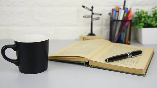 Panning cup of hot coffee and books on table