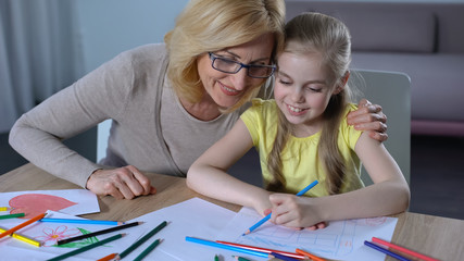 Grandmother spending time with granddaughter and teaching her painting, family
