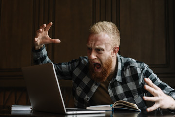 Freelancer missed deadline for project, he angry and nervous, big problems. Bearded man with emotional face shouting loudly on laptop computer display, fired from work. Failure business concept