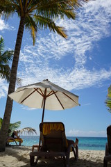 Sit on the Chairs and Umbrella in palm beach with clear blue sky on vacation day