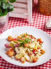 Salad with salmon, vegetables and mixed greens on white plate. Close up