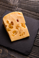 Piece and slices of cheese on a wooden background