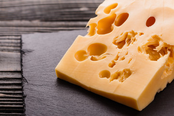 Piece and slices of cheese on a wooden background