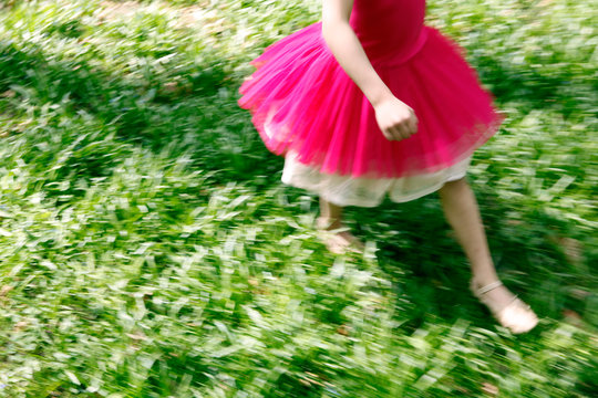 Glückliches Mädchen läuft über Wiese in rotem Kleid