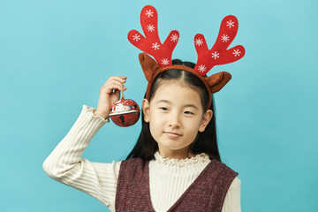 Asian girl with a Christmas concept headdress Child, Close up of cute little asian girl on blue background isolated.