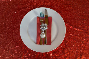 White dish with cutlery and christmas decoration, red background