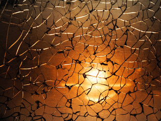 Cracks on broken glass texture, backlight. Mirror,  shattered background. Abstract crack pattern, orange and brown tones