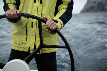  A sailing yacht skipper is at the helm. Close-up. It's cold, waves. - obrazy, fototapety, plakaty