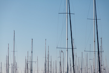  Masts of yachts, which stand in the marina against the blue sky.