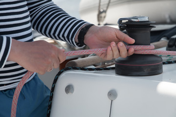  Men's hands are pulling the sheet with the help of a winch.