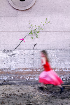 Gl&uuml;ckliches  M&auml;dchen l&auml;uft in rosa Kleid vor Mauer