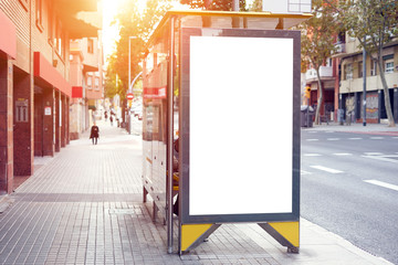 Empty white advertising urban billboard near city bus stop, placeholder template on a street, space for design layout. sunset.