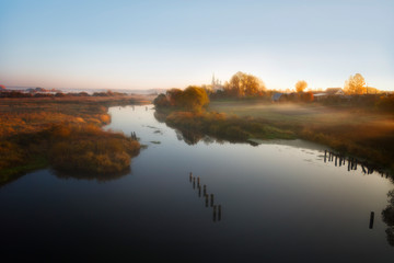 Landscape with river and old church afar on an autumn morning