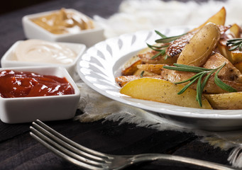 Homemade organic vegetable vegan vegetarian baked potato wedges with rosemary and sauces.