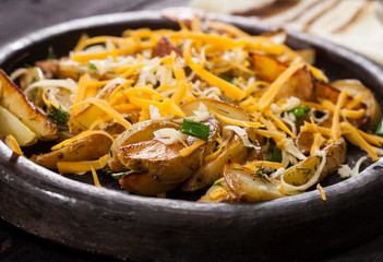 Homemade organic vegetable vegan vegetarian baked potato wedges with cheese, chives and dill