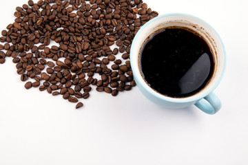 coffee mug with coffee beans on a white table, with copy space