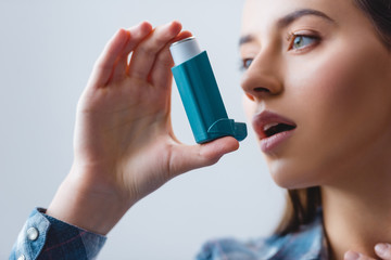 close-up view of young woman with asthma using inhaler - Powered by Adobe
