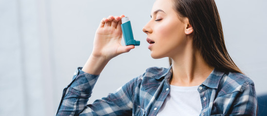 girl using inhaler while suffering from asthma at home - obrazy, fototapety, plakaty