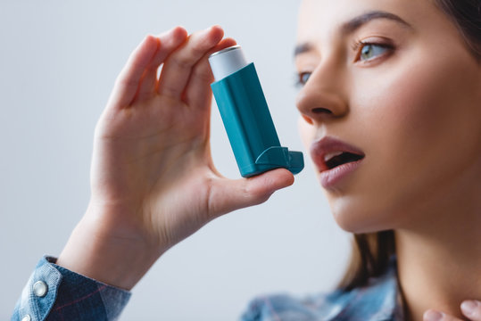close-up view of young woman with asthma using inhaler