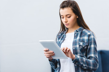 Fototapeta premium beautiful girl in checkered shirt using digital tablet at home