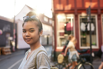 Smiling young Asian woman standing on a city street