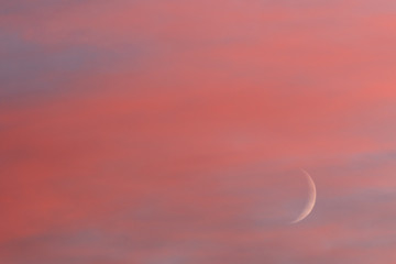 Young moon in colorful red clouds in sunset time