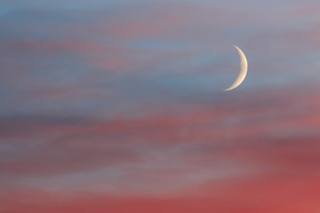 Young moon in colorful clouds in sunset time