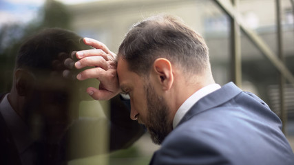 Stressed businessman banging head wall, work troubles pressure, disappointment