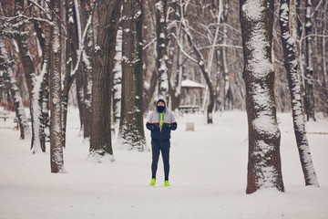 Man jogging in a cold winter snowy day outdoors.