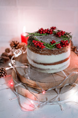Christmas chocolate vanilla cake. Rustic homemade cake. Piece of cake. Vegan raw cake. Decorated rosemary and christmas tree. Lights and sparkler. Candle and garland on the background. 