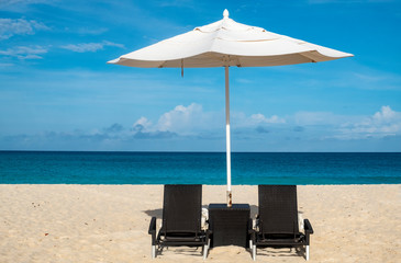 A White Umbrella and Black Chair on a Caribbean Beach on a Sunny Day